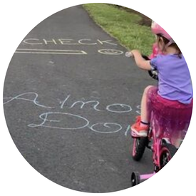 A little girl riding her bike while wearing a helmet.