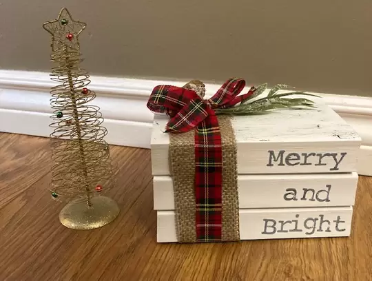 A christmas themed book stack with a bow and the words "Merry and Bright"