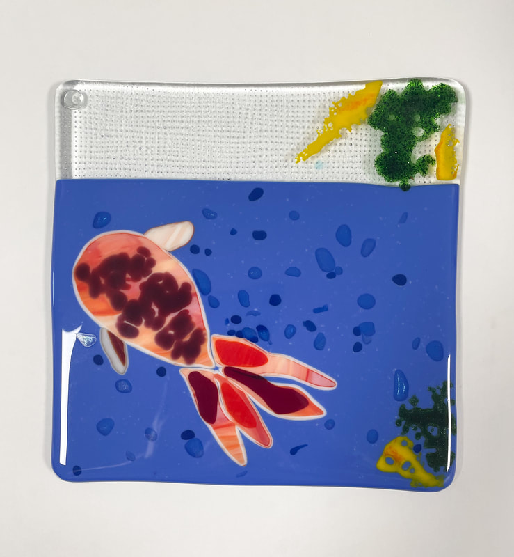 A glass tile featuring a red fish.
