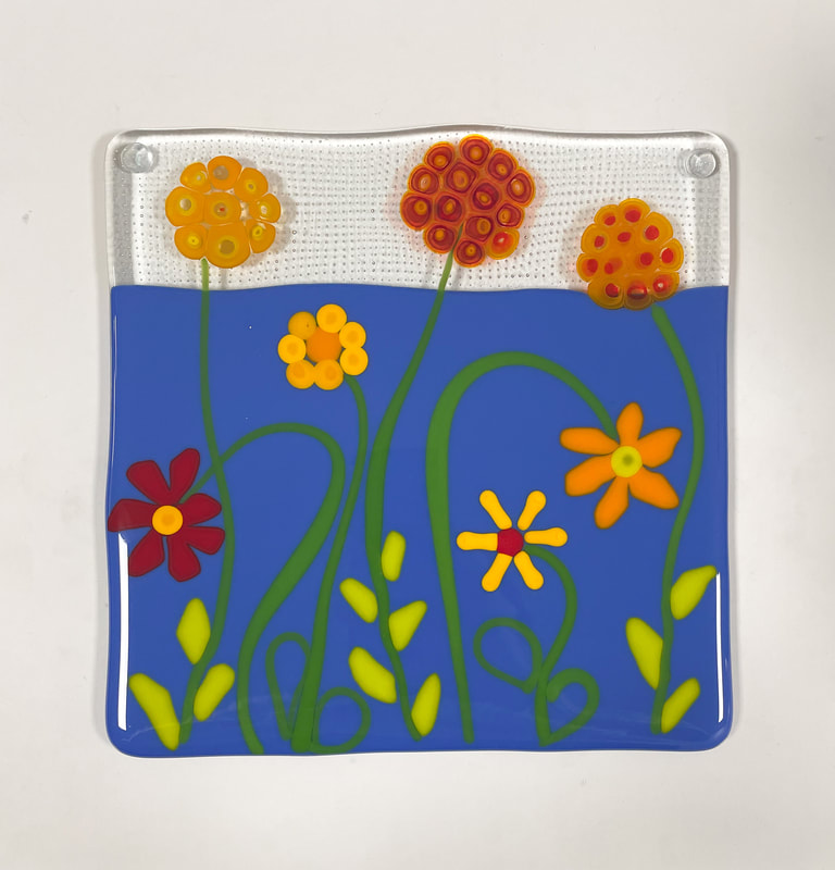A glass tile featuring red and orange flowers.