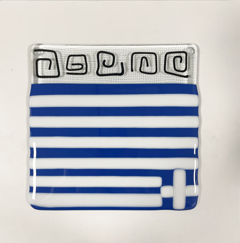 A glass tile featuring blue and white stripes and black squiggles.