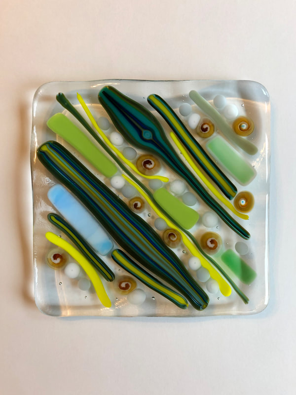 A glass tile featuring green and yellow stripes and blobs.