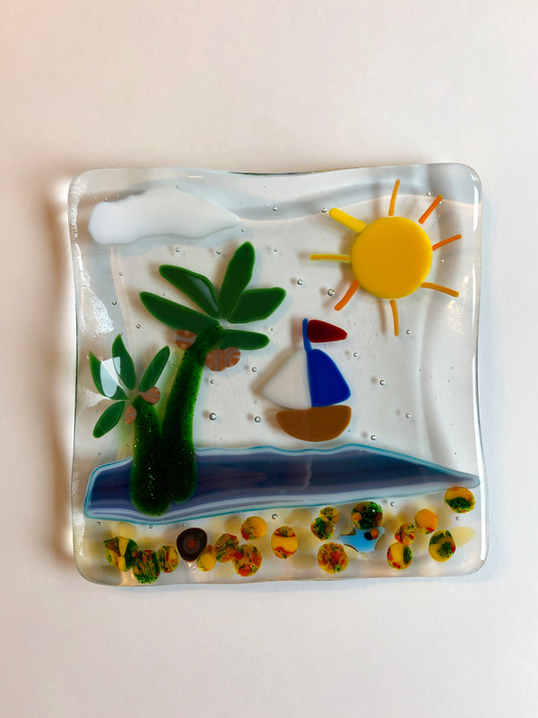Glass tile art featuring a boat and an island. 