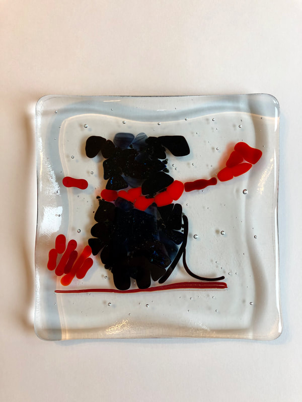 A glass tile with a black dog on a red collar.