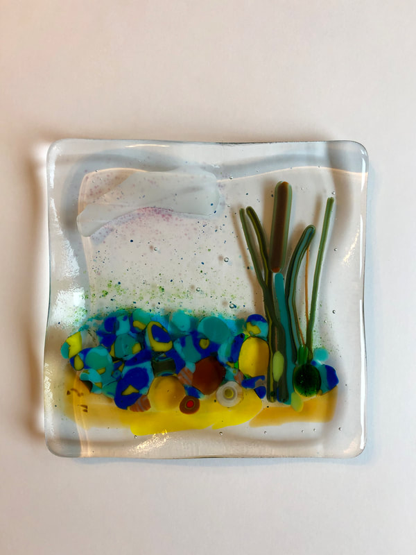 A glass tile featuring an abstract image of a beach scene.