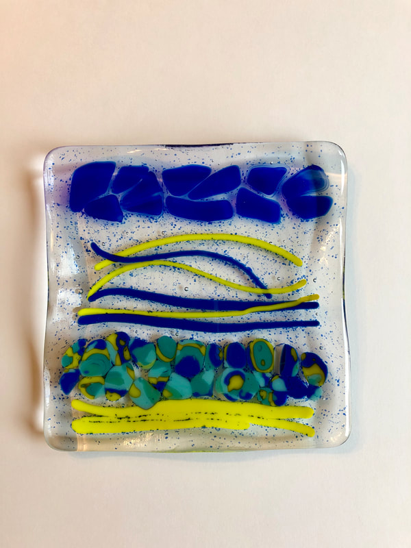 A glass tile featuring blue and yellow scene of a beach.