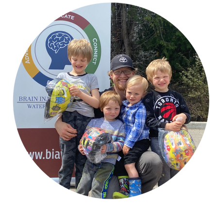 A smiling dad hugging his kids who just received free helmets from BIAWW.