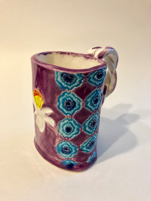 A patterned mug with blue designs on a purple mug.