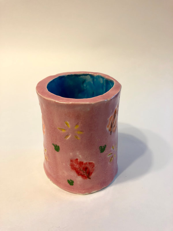 A pink mug with yellow flowers and red hearts.