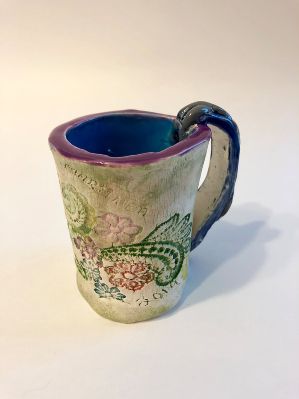 A light grey mug with a blue inside and flowers on the outside.