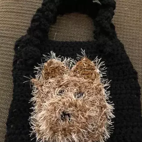 A crochet purse with a brown dog on it.